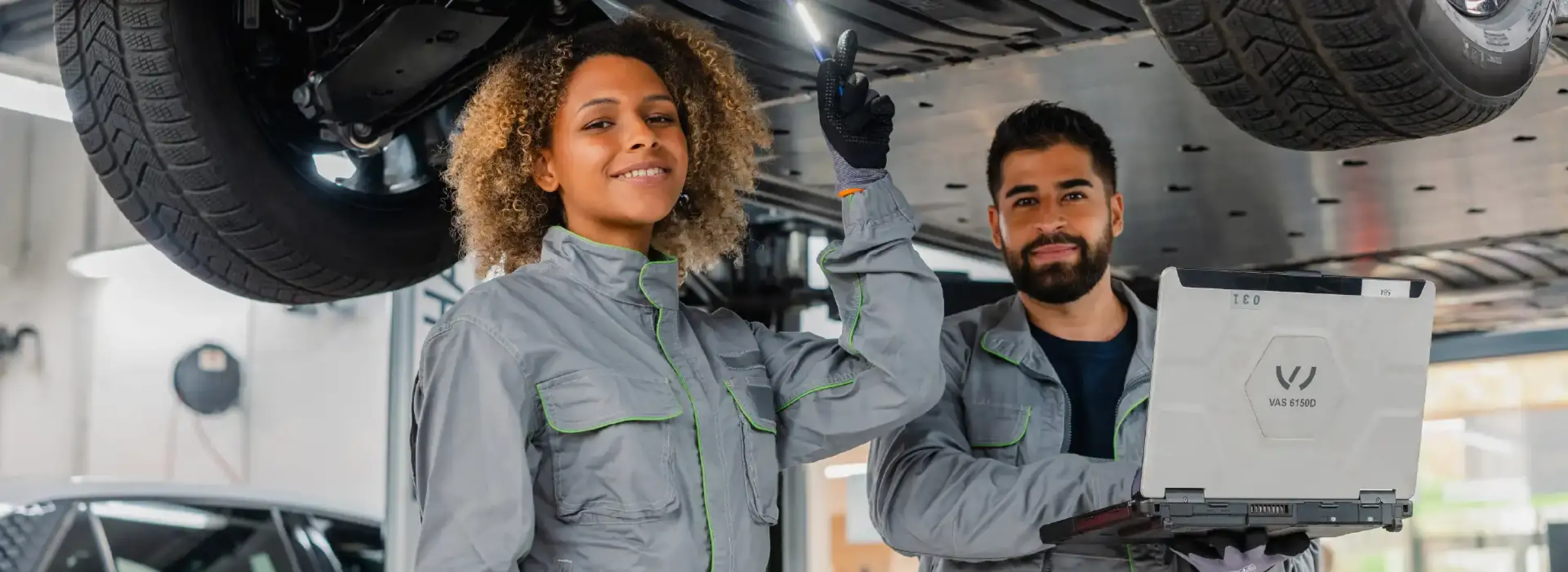 Werkstattmitarbeitende stehen unter Firmenfahrzeug und f&uuml;hren profesionelle Reparatur durch mit Originalteile und Originalzubeh&ouml;r