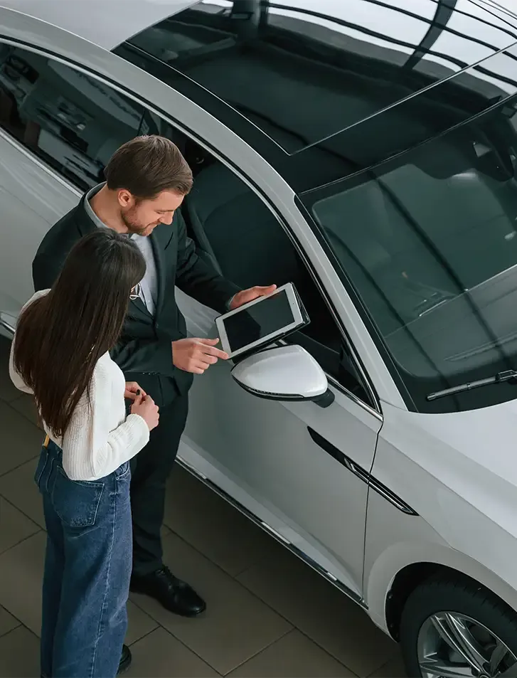 Menschen mit iPad am Auto im Autohaus