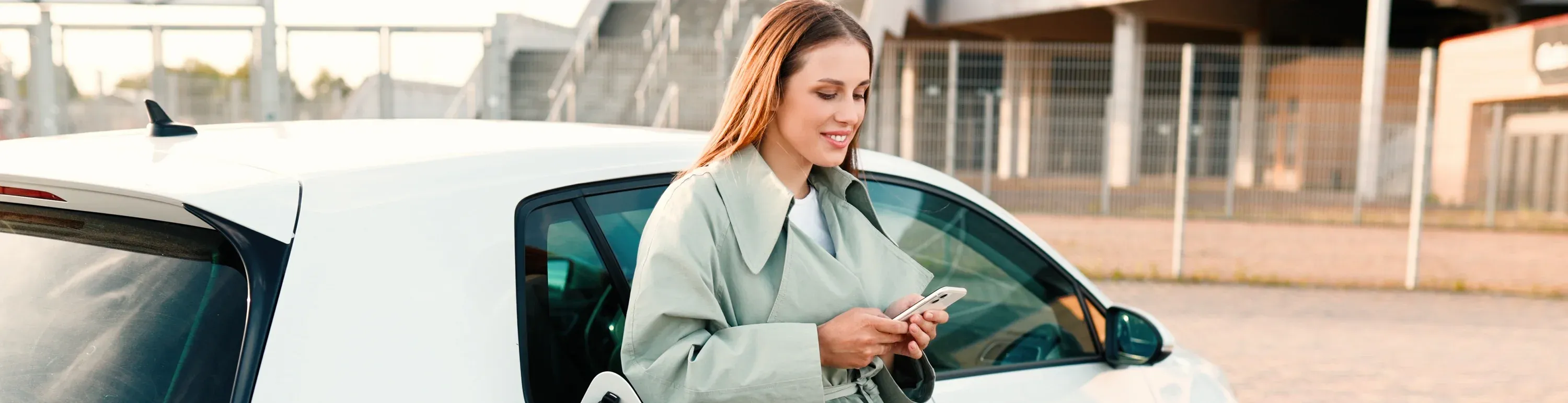 Frau mit Handy am Auto