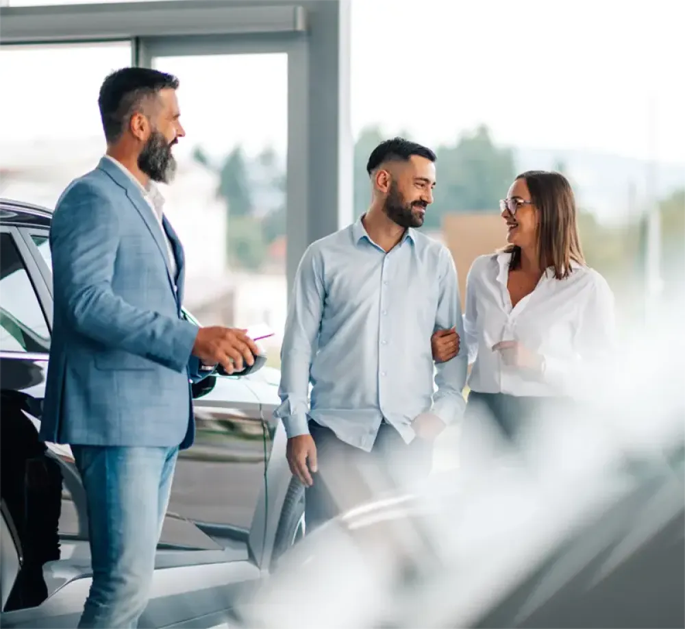 Handelsvertreter, der das Paar bei der Autoauswahl beim Fahrzeug-H&auml;ndler unterst&uuml;tzt