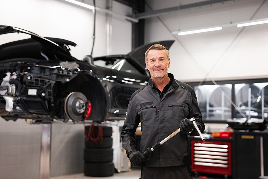 Service-Mitarbeiter l&auml;chelt freundlich in die Kamera und ist bereit f&uuml;r Ihre Reparatur des Firmenfahrzeuges &ndash; und f&uuml;r Sie als Gro&szlig;kunde gibt es zus&auml;tzlich noch spezielle Rabatte